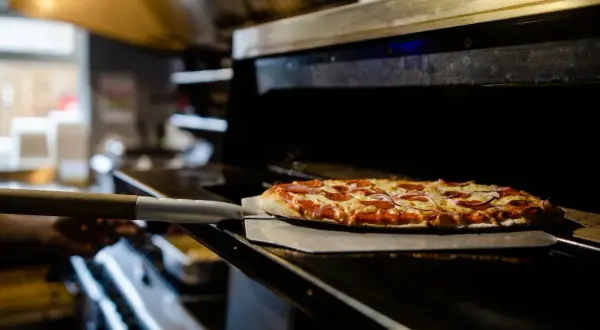 Piec z pizzą na łopacie, gotową do wyjęcia.